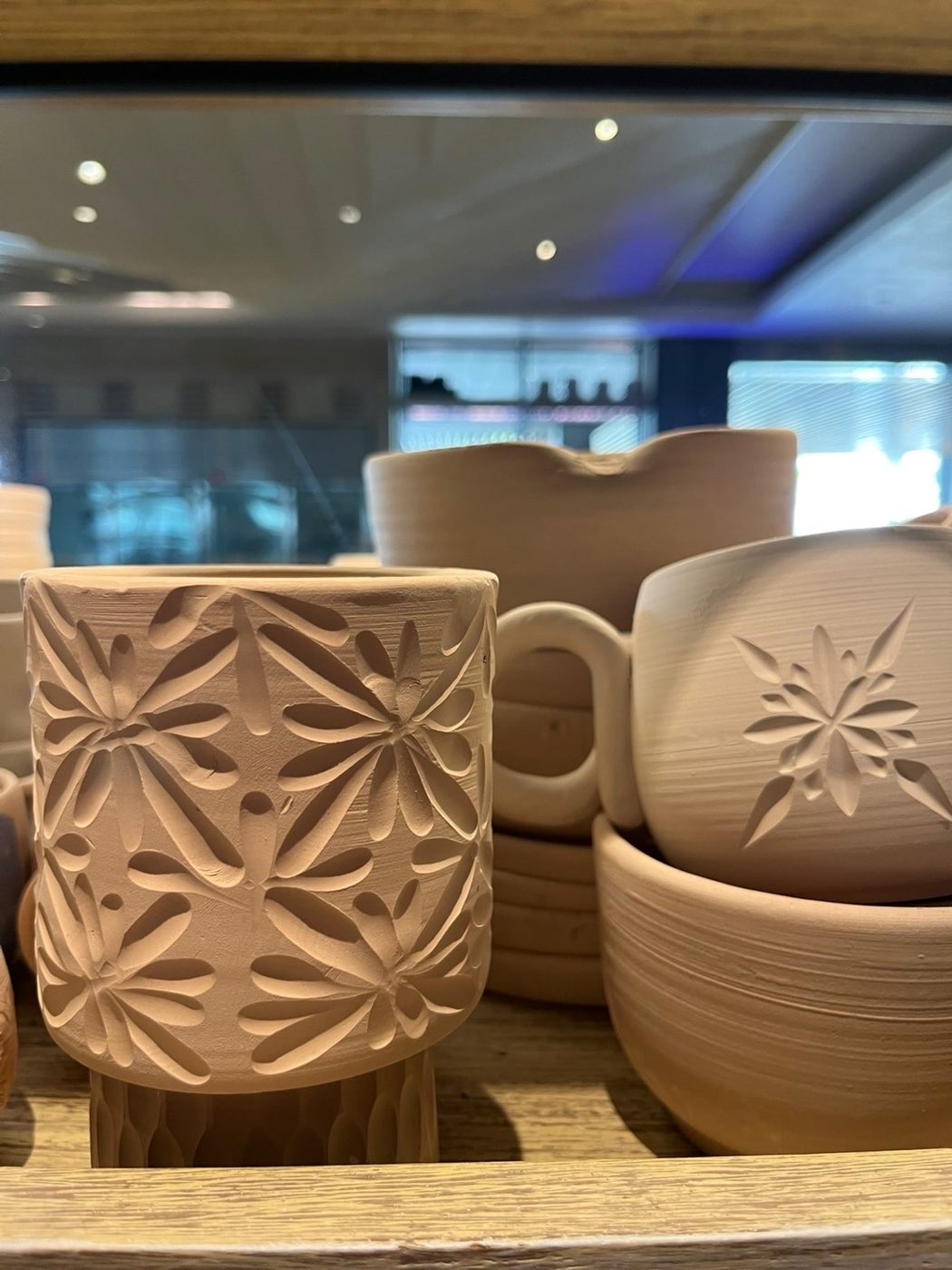 Gobelet en terre gravé d'un motif floral, sur une étagère d'atelier à Bali