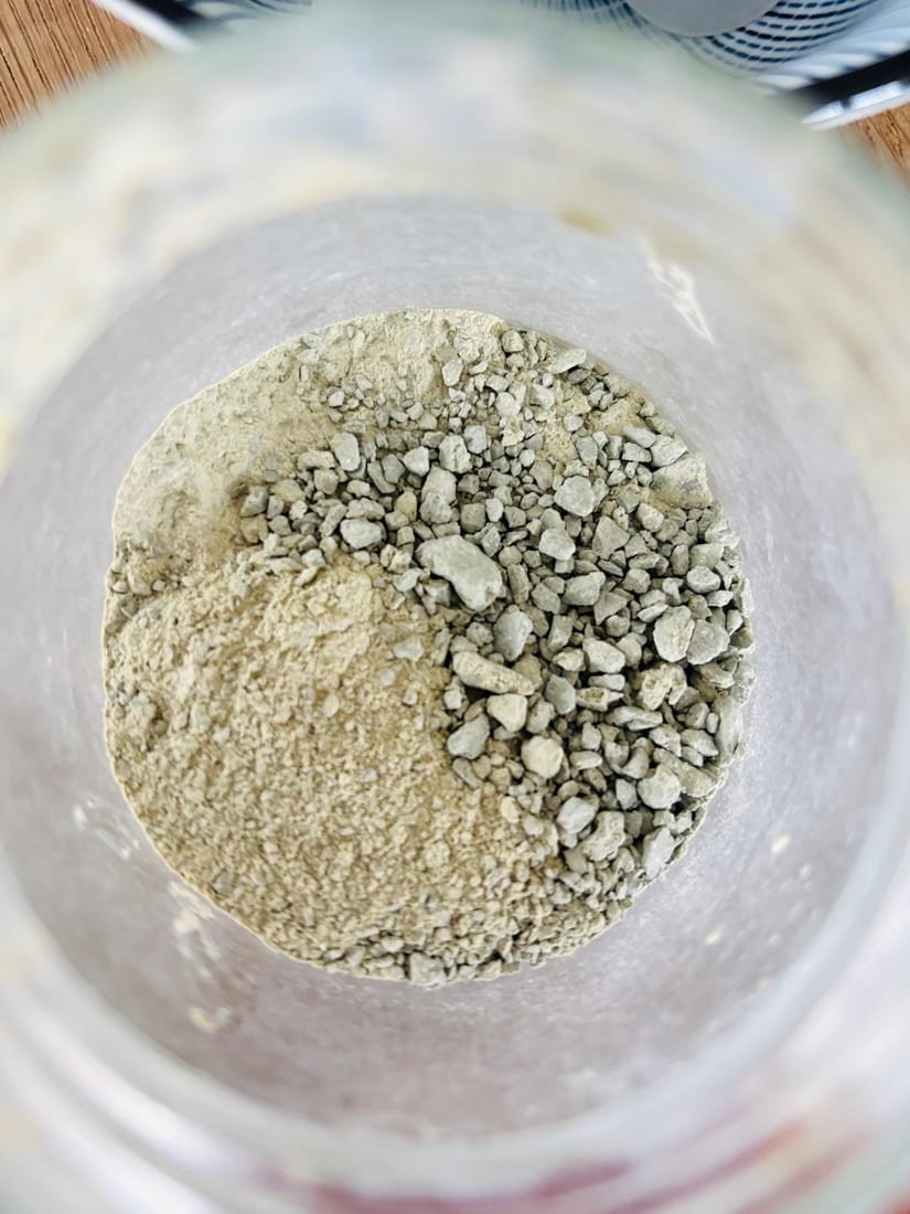 Poudre d'argile verte et petits granules dans un pot en verre